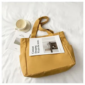 Detail shot of yellow canvas tote bag, large capacity solid color shoulder bag for daily commuting.