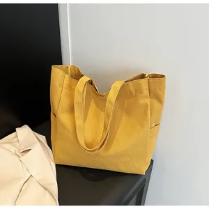 Detailed view of the solid yellow canvas tote bag, featuring sturdy handles and side pockets.