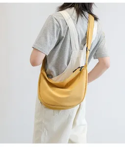 Sac bandouliere en toile jaune detail montrant le tissu souple, la sangle et la fermeture.