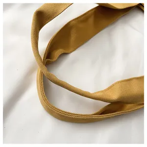 Close-up detail of yellow canvas tote bag straps showing clear fabric texture weave.