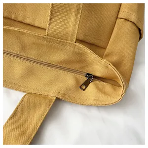 Canvas tote bag detail close-up, durable yellow fabric, smooth zipper, reinforced shoulder strap.