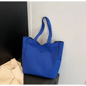 Detail view of casual royal blue canvas tote bag, shoulder bag with side pockets and straps.