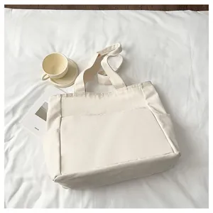 Detailed view of the solid color canvas tote bag showing front pocket and sturdy double handles.