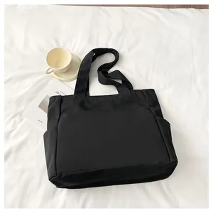 Minimalist black canvas tote bag with large capacity, durable shoulder straps for daily use.
