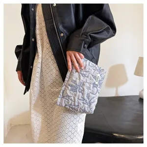 Detailed view of grey floral yarn-dyed fabric cosmetic pouch and elegant clutch bag.