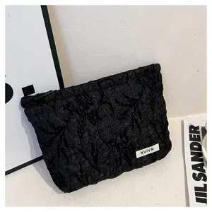 Black textured cosmetic bag detail shot, compact pouch with unique pleated design for daily use.