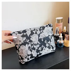 Elegant black and white floral fabric cosmetic bag with large capacity, chic storage pouch.