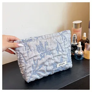 Close-up detail view of silver textured fabric cosmetic pouch featuring unique crinkled design.