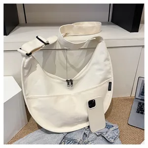 Vue détaillée du sac bandoulière croissant en toile blanche avec fermeture éclair.