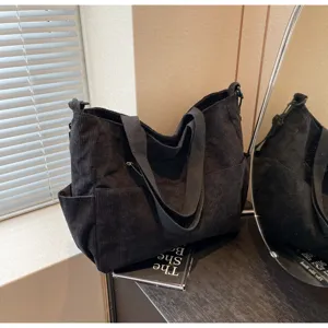 Detailed view of black corduroy tote bag showing spacious interior, texture and front pockets.