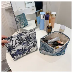 Blue and white floral tapestry makeup bag detail view with zipper and storage space.