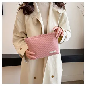 Detailed view of the pink corduroy makeup bag, showing textured fabric and portable design.