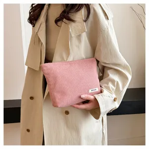 Pink corduroy makeup bag detail, soft fabric texture with clean stitching and stylish label accent.