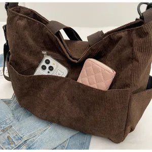 Brown corduroy tote bag detail showing front pocket capacity with phone and wallet inside.