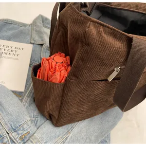 Brown corduroy shoulder tote bag detail view, casual retro style with front pocket and zipper.