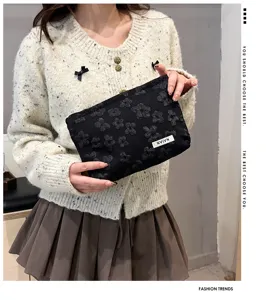 Detailed view of black floral textured cosmetic bag, portable clutch pouch with label.