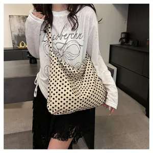 Detailed shot of stylish polka dot canvas shoulder bag, slouchy hobo tote design for daily wear.