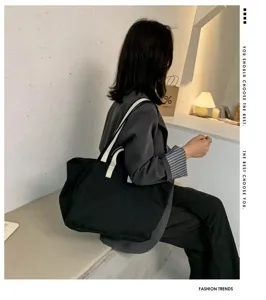 Detail view of black canvas tote bag with white straps in modern minimal interior setting scene