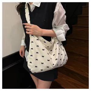 Casual canvas shoulder bag for women, featuring a cute allover black bow print design.
