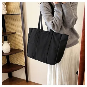 Black canvas tote bag detail showing front pocket, sturdy handles and minimalist daily style.