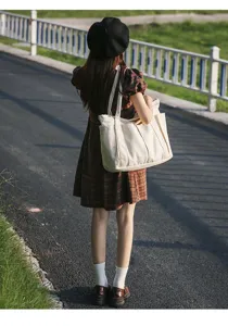 Detail view of large canvas tote bag featuring exterior pockets and durable daily straps.