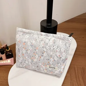 Detail view of the delicate lace cosmetic bag featuring elegant floral pattern and zipper.