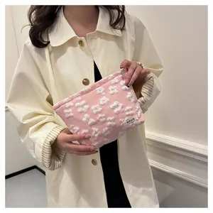 Detailed close-up view of a pink cosmetic pouch with lovely white embroidered flower patterns.