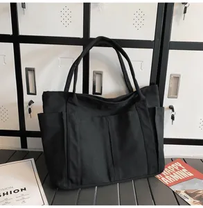 Black canvas tote bag for women, casual shoulder bag with multiple exterior pockets for daily use.