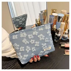 Blue quilted cosmetic pouch with floral pattern, portable makeup bag detailed view for daily use.