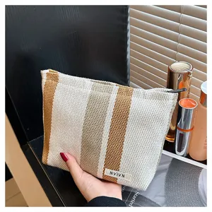 Detail view of the striped linen cosmetic pouch, showing textured fabric and zipper closure.