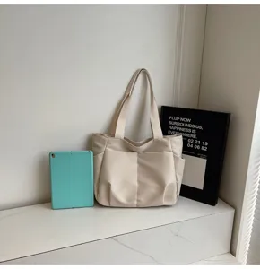 Detail view of minimalist beige tote bag with front pockets on clean white background scene.
