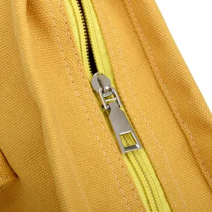 Close-up detail of yellow canvas bag zipper, smooth metallic puller and durable fabric.