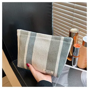 Close-up detail of green and white striped makeup bag, portable canvas cosmetic pouch.