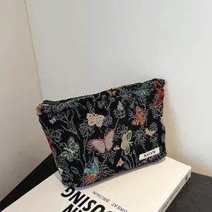 Black fabric cosmetic bag with colorful butterfly tapestry pattern, detailed view showing zipper.