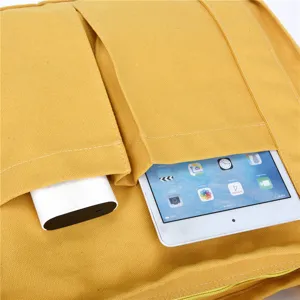 Yellow canvas tote bag detail view showing front pockets with tablet and power bank storage capacity.
