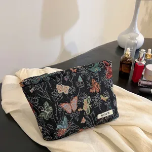 Detail shot of a black woven cosmetic pouch featuring colorful butterfly patterns.