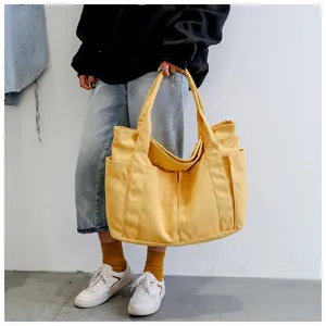 Detail view of large yellow canvas tote bag, casual daily shoulder bag with pockets.