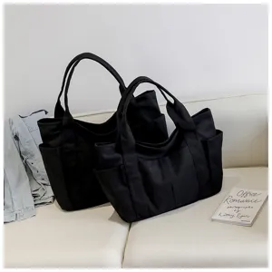 Detail view of black canvas tote bag featuring large capacity and multiple pockets.