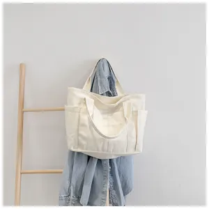 Minimalist white canvas tote bag with side pockets, casual shoulder bag for daily use.