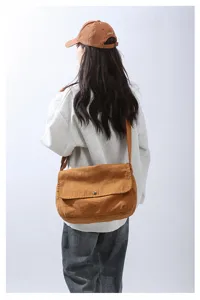 Detailed view of brown canvas messenger bag with flap and button, casual student style shoulder bag.