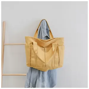 Yellow canvas shoulder bag detail showing multiple outer pockets and large capacity design.