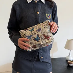 Close-up detail of the butterfly patterned fabric cosmetic storage pouch held by hand.