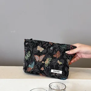 Detailed view of the woven makeup bag with colorful butterfly pattern and secure zipper closure.