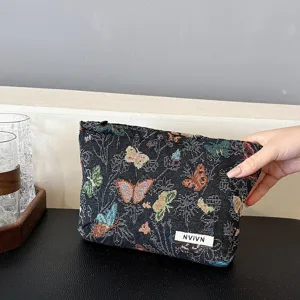 Detailed close-up of a black woven fabric cosmetic pouch featuring colorful butterfly patterns.
