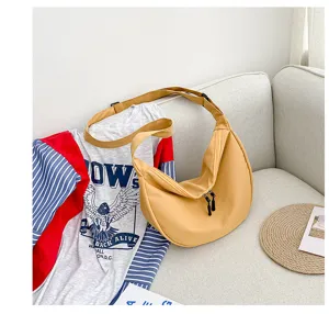 Vue détaillée du sac bandoulière en toile jaune décontracté, au design souple en forme de croissant.