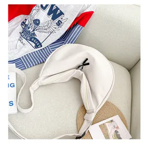 Détail du sac croissant en toile blanche minimaliste avec fermeture éclair lisse et sangle.