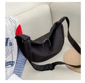 Vue détaillée d'un sac bandoulière en toile noire avec sangle réglable et fermeture zippée.
