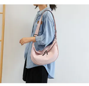 Detail du sac a bandouliere en toile rose, avec sangle reglable et fermeture eclair solide.