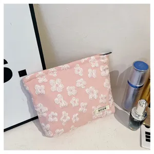 Pink cosmetic bag with textured white flowers, portable makeup pouch for daily travel use.