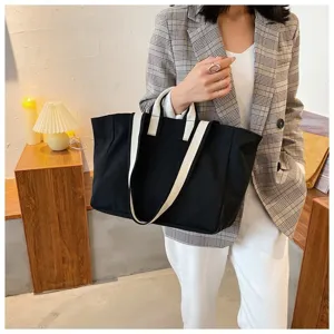 Black canvas tote bag detail, minimalist design with contrast white straps for daily commute.